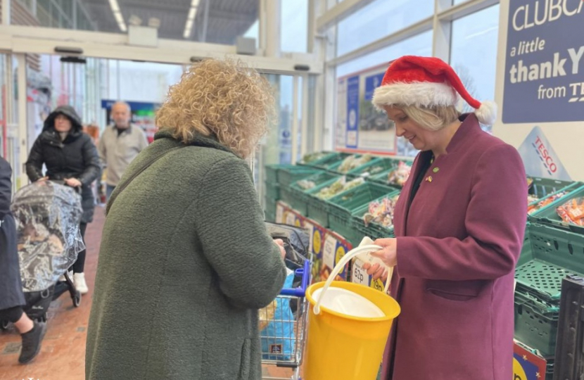 Katherine Fletcher with a charity bucket in her hand, speaking to someone in a supermarket.