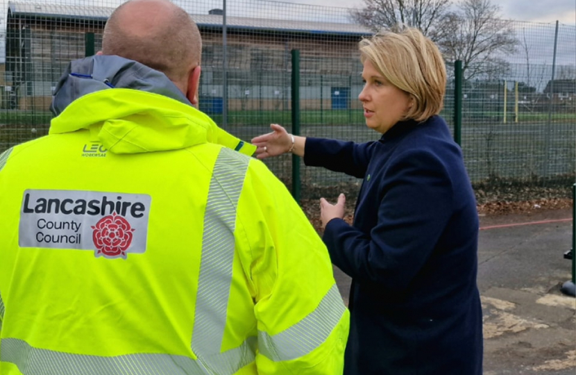 Katherine Fletcher on a school playground, talking to a man in a high-vis jacket. The jacket has the Lancashire County Council logo visible on the back.