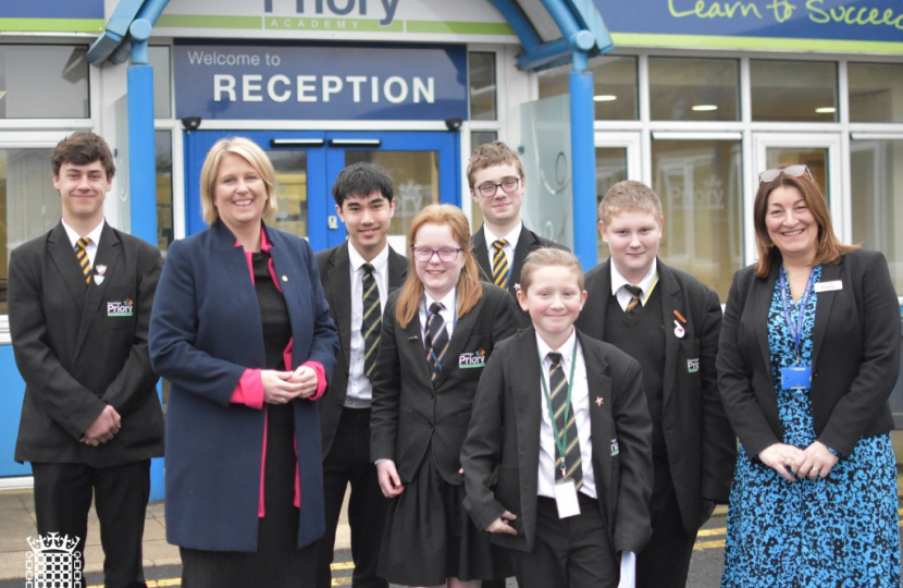 Katherine Fletcher stood outside Penwortham Priory Academy with a group of students and the vice principal.