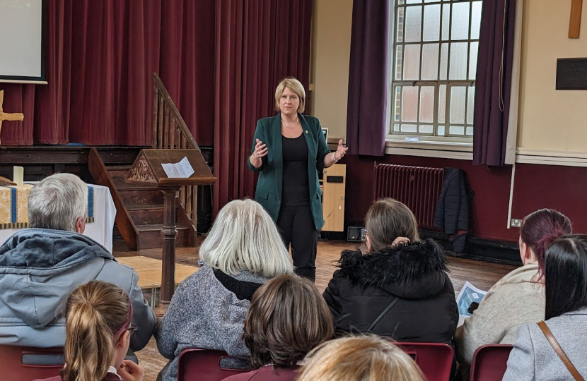 Katherine talking to a group of people at the front of Hutton Grammar school hall