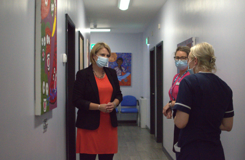 Katherine in medical setting talking to staff and wearing a medical mask