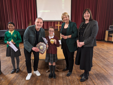 Olivia being presented with her trophy. Katherine Fletcher, Nicola Moran and Graham Liver also in the picture and there is another child standing next to them holding a certificate.