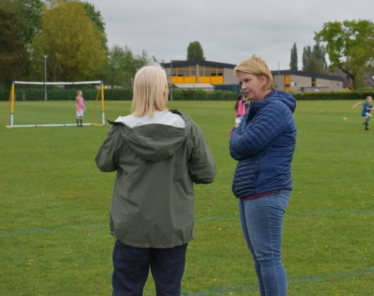 Katherine standing on a football pitch talking to another woman